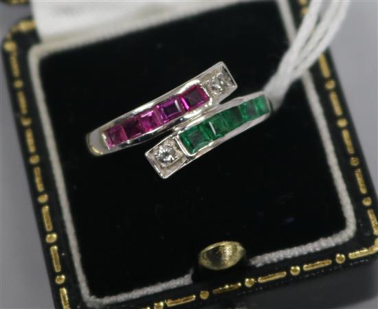 A white gold, ruby, emerald and diamond channel set crossover ring, size O.